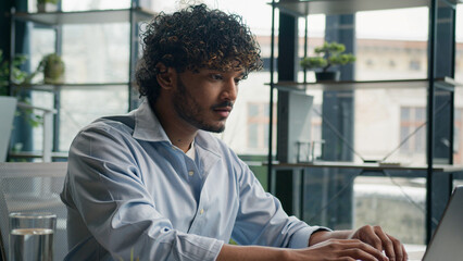 Business portrait Indian arabian man smiling male businessman cheerful guy gen z working on laptop computer studying online at office ethnic hispanic manager employee looking at camera toothy smile