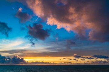 Vibrant sunset over ocean with dramatic clouds.