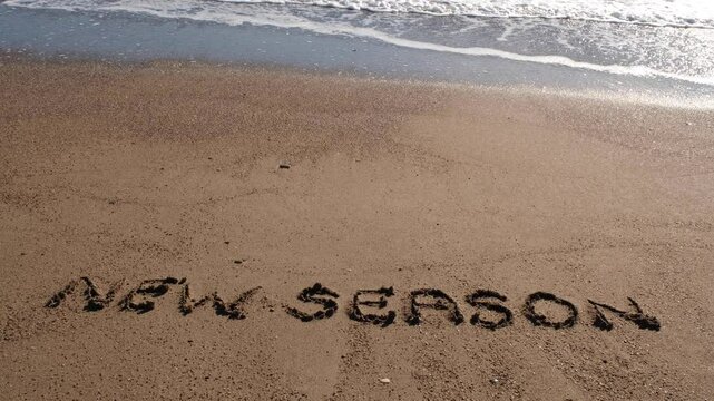 New season inscription on the beach and the dog that passes behind it