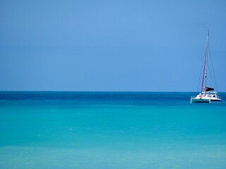 Fototapeta premium Catamaran on calm turquoise sea under a clear blue sky.