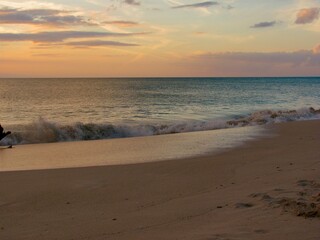 Golden sunset reflecting on gentle ocean waves by the shore.