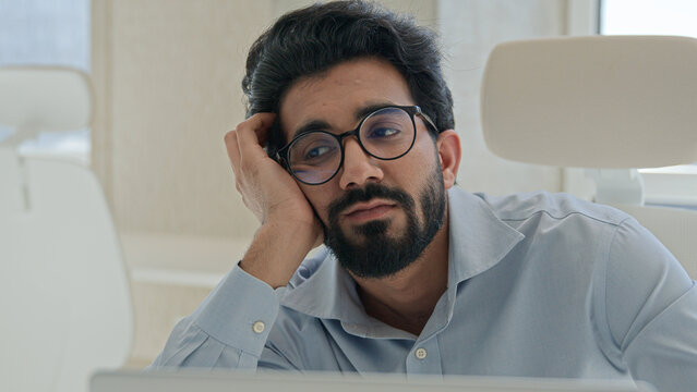 Sleepy tired Arabian Indian man businessman lazy worker employee manager working boring online job in office feel depression burnout low energy apathy fatigued overwork unwell male guy with weariness 