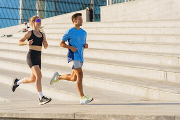 Fototapeta premium Athletes jog together on outdoor steps in a sunny urban environment during morning exercise