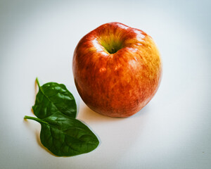 close-up of red apple and green spinach on a white background healthy eating theme