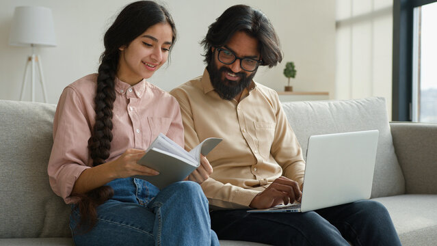 Multiracial couple Arabian Indian adult man and woman read paper notes pay bills loan mortgage business payment planning family budget diverse wife and husband use laptop check finances in living room - Powered by Adobe