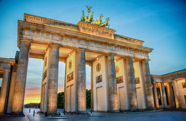 Built in 1873, the sandstone Brandenburg Gate, the symbol of German unity, has its fluted, Doric columns, lighted for the upcoming evening at blue hour in Berlin, Germany on a summer evening.