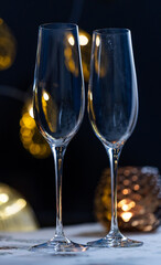 concept of celebrating christmas and new year, two glasses of champagne on the background of candles and colorful garlands, warm home traditional festive atmosphere