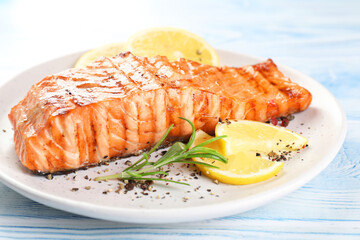 Delicious grilled salmon fillet served on light blue wooden table, closeup