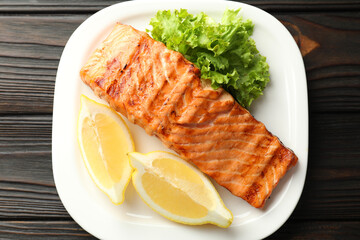 Delicious grilled salmon fillet served on wooden table, top view