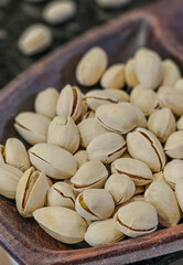 Whole pistachios in shells, arranged in a wooden bowl with a blurred background