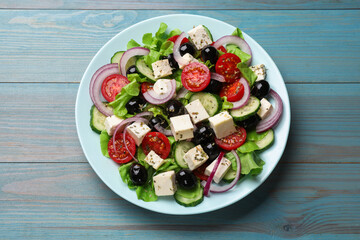Delicious salad with feta cheese on blue wooden table, top view