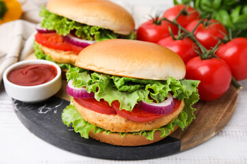 Delicious vegetarian burgers with chickpea cutlets, tomatoes and sauce on white table, closeup