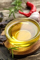 Cooking oil in bowl, red basil and rosemary on wooden table, closeup