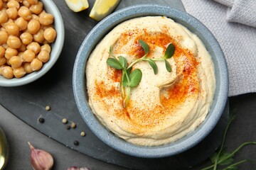 Delicious hummus with paprika and chickpeas served on dark grey table, flat lay.