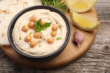 Delicious hummus with chickpeas and pita served on wooden table