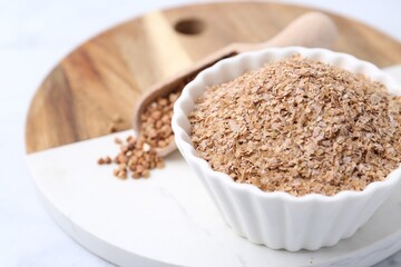 Buckwheat bran in bowl on white table, closeup. Space for text