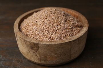 Buckwheat bran in bowl on wooden table, closeup