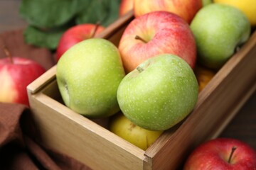 Fresh ripe apples in wooden crate on table, closeup