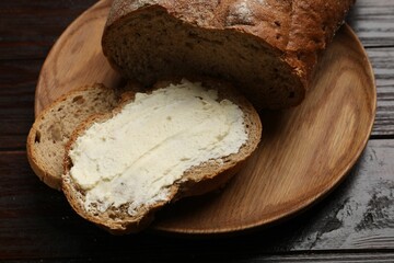 Fresh bread with butter on wooden table, closeup