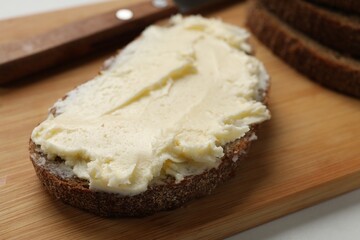 Fresh bread with butter on white table, closeup