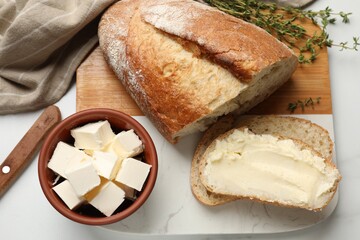 Fresh bread with butter and thyme on white table, flat lay