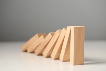Domino effect. Wooden blocks falling on white table, closeup