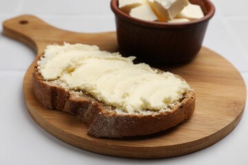 Fresh bread with butter on white tiled table, closeup
