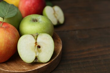Different ripe apples on wooden table, closeup. Space for text