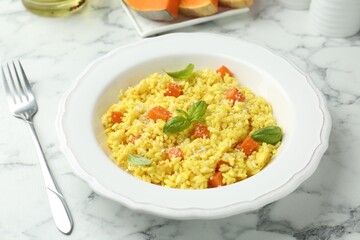 Delicious pumpkin risotto served on white marble table, closeup