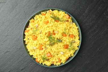 Delicious pumpkin risotto in bowl on black table, top view