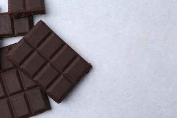 Pieces of delicious dark chocolate on light table, top view. Space for text