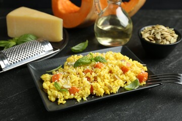 Delicious pumpkin risotto served on black table, closeup