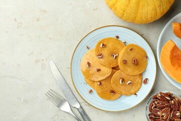 Tasty pumpkin pancakes with nuts served on light grey table, flat lay. Space for text
