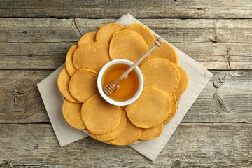 Tasty pumpkin pancakes and honey on wooden table, top view