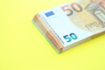 Big amount of one hundred and fifty euro money bills on yellow background