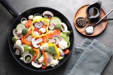 Frying pan with mix of vegetables, mushrooms and spices on grey table, top view