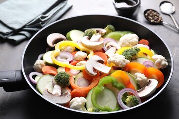 Frying pan with mix of vegetables, mushrooms and spices on grey table, closeup
