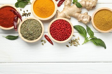 Different aromatic spices on white wooden table, flat lay. Space for text