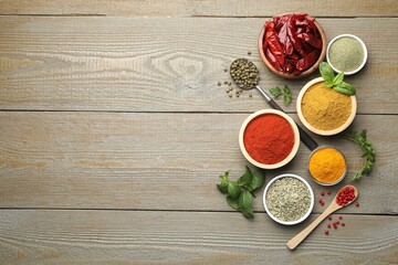 Different aromatic spices on wooden table, flat lay. Space for text