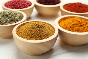 Different aromatic spices on white wooden table, closeup