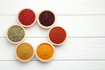 Different aromatic spices on white wooden table, flat lay