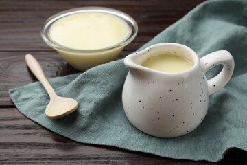 Condensed milk and spoon on wooden table, closeup