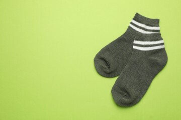 Pair of soft socks on light green background, top view. Space for text