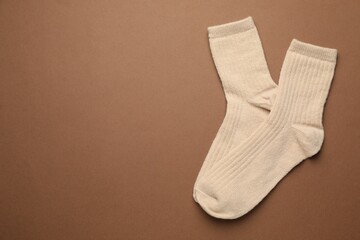 Pair of soft socks on light brown background, top view. Space for text