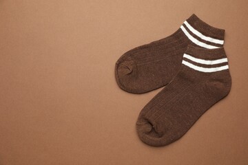 Pair of soft socks on light brown background, top view. Space for text