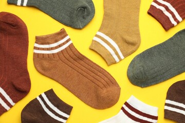Different soft socks on yellow background, flat lay