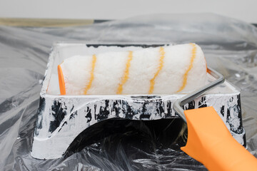 Paint roller is sitting on a tray with a white paint roller