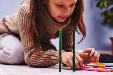 Girl playing with markers on the floor: child engrossed in creat
