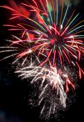 Red, green and yellow fireworks exploding on black backdrop