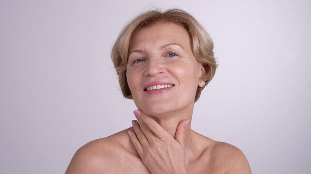 Portrait of a mature lady touching her neck and shoulders. Graceful female embracing her natural beauty and positive aging. 4k high res